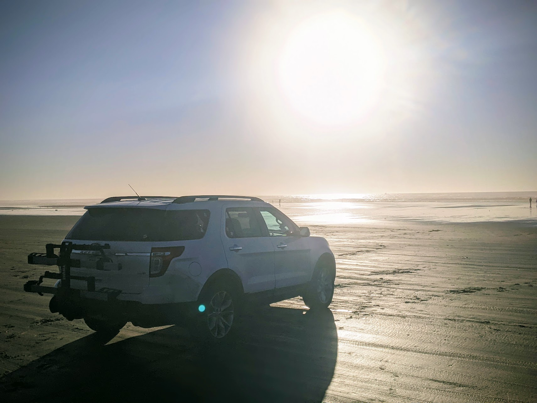 A Ford Explorer sits alone on the beach, watching the sunset.