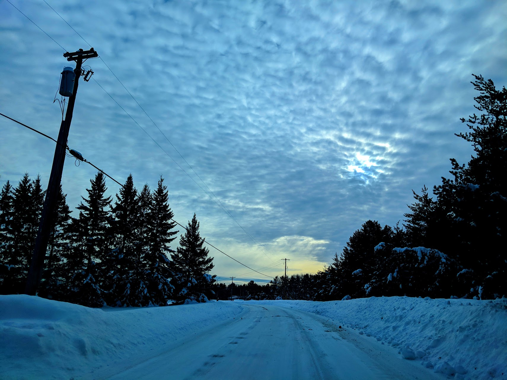 Snow-covered road with a bright cloudy sky in the Midwest.
